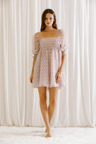 Model wearing a lilac mini dress with mini daisies embroidery and puffy sleeves