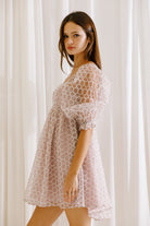 Side view of a model wearing a lilac mini dress with mini daisies embroidery and puffy sleeves
