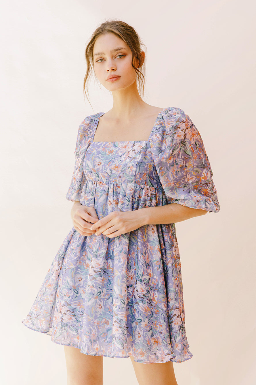 Woman wearing a purple paint stroke print dress against a plain background
