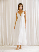 Woman wearing a white dress standing in front of white curtains