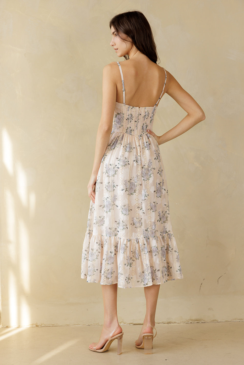 Back view of a woman wearing a floral dress with a beige background