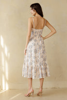 Back view of a woman wearing a floral dress with a beige background