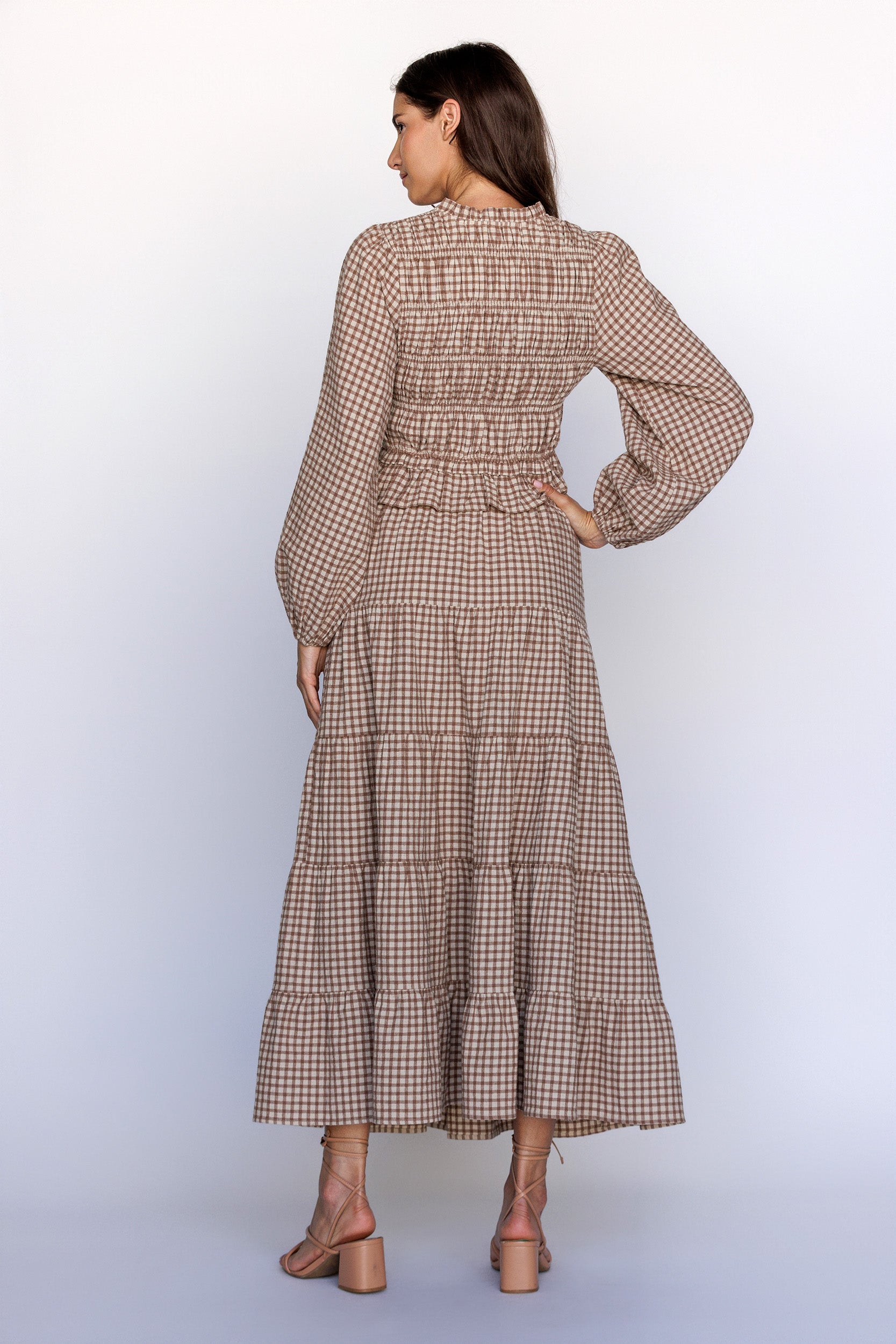 Back view of a woman wearing a brown beige gingham smocked top with matching skirt set on a white background