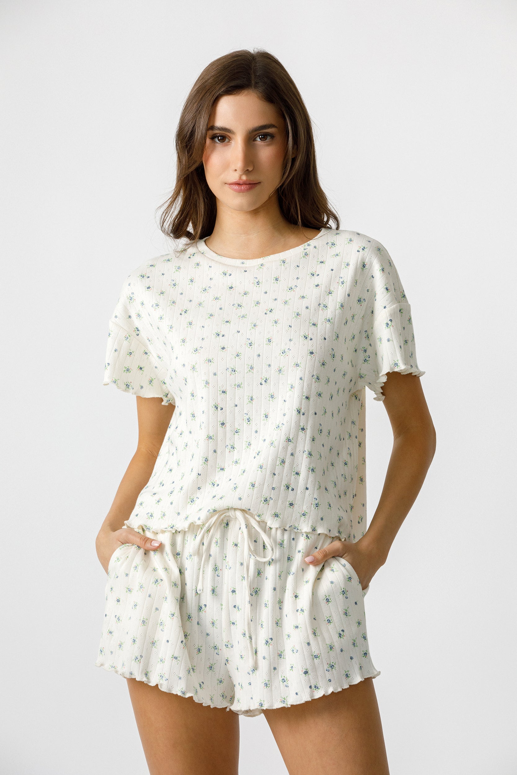 Woman wearing a cream blue floral pajama set on a plain background