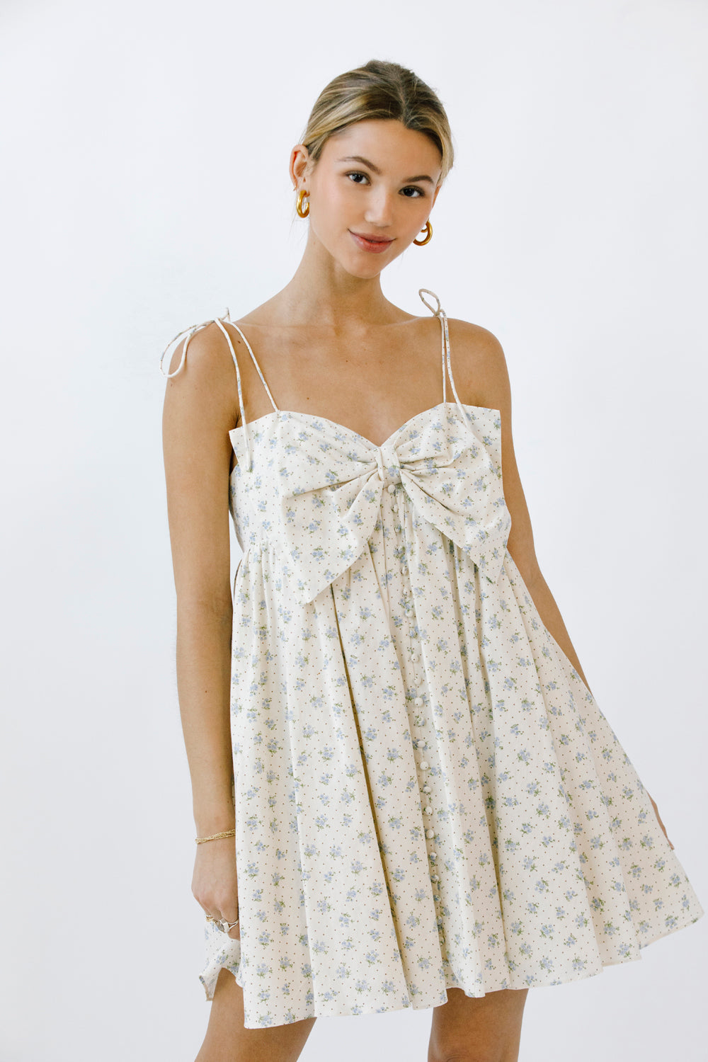 Woman wearing a floral dress with a bow detail on a white background