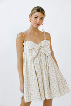 Woman wearing a floral dress with a bow detail on a white background