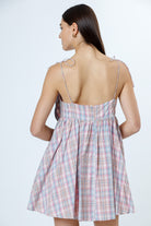 Woman wearing a plaid dress with thin straps on a white background