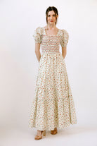 Woman wearing a floral maxi dress and beige heels on a white background