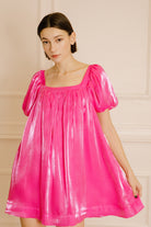 Woman wearing a pink nightgown against a beige wall