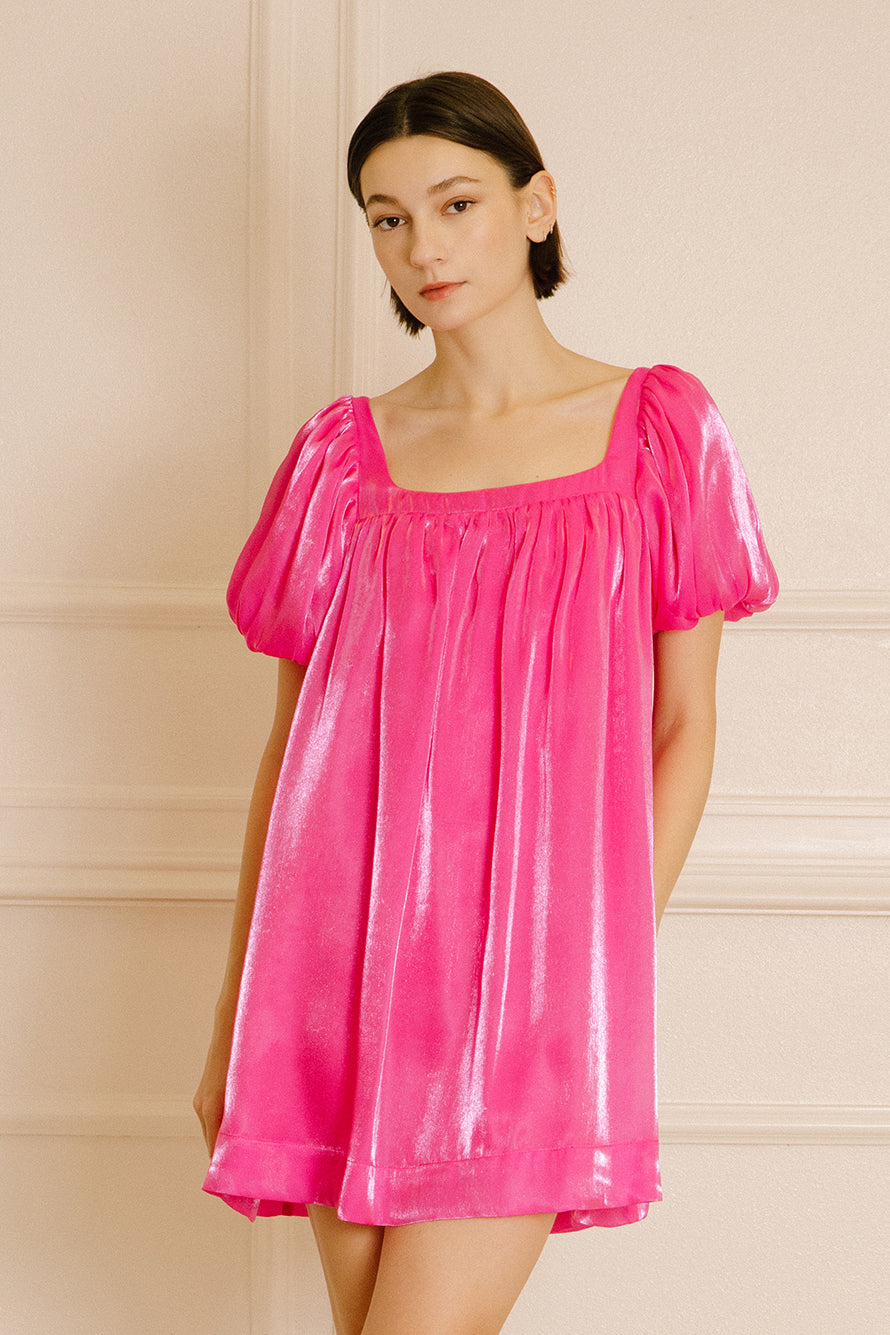 Woman wearing a pink nightgown silhouette against a beige wall