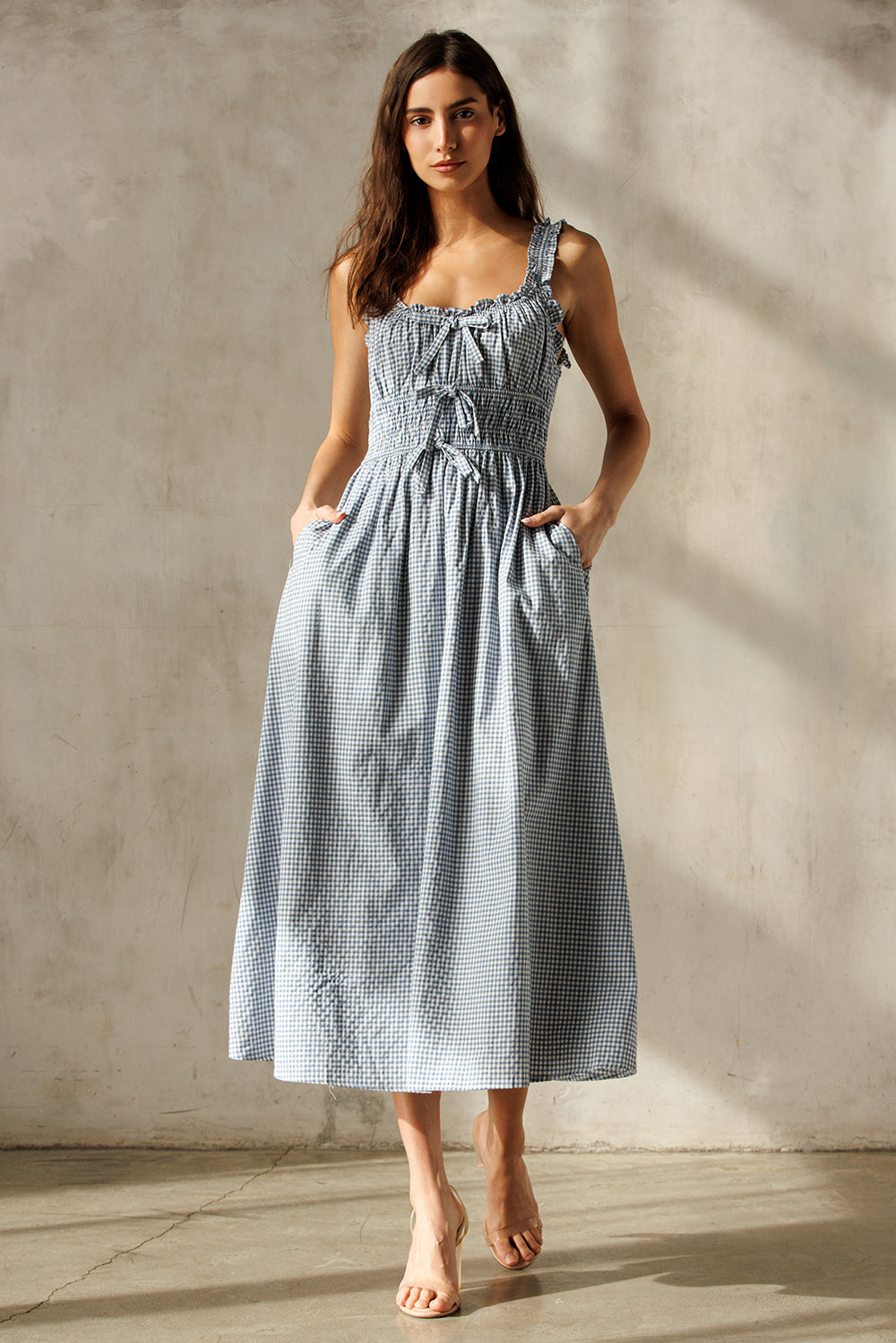 Woman wearing a blue checkered dress against a neutral background