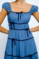 Blue dress with navy trim on a white background