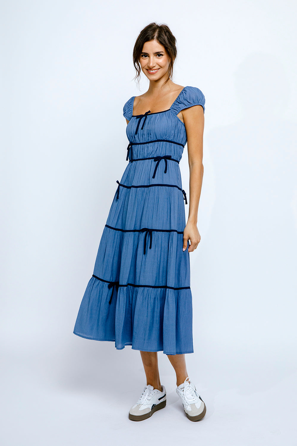 Woman wearing a blue dress with navy accents on a white background