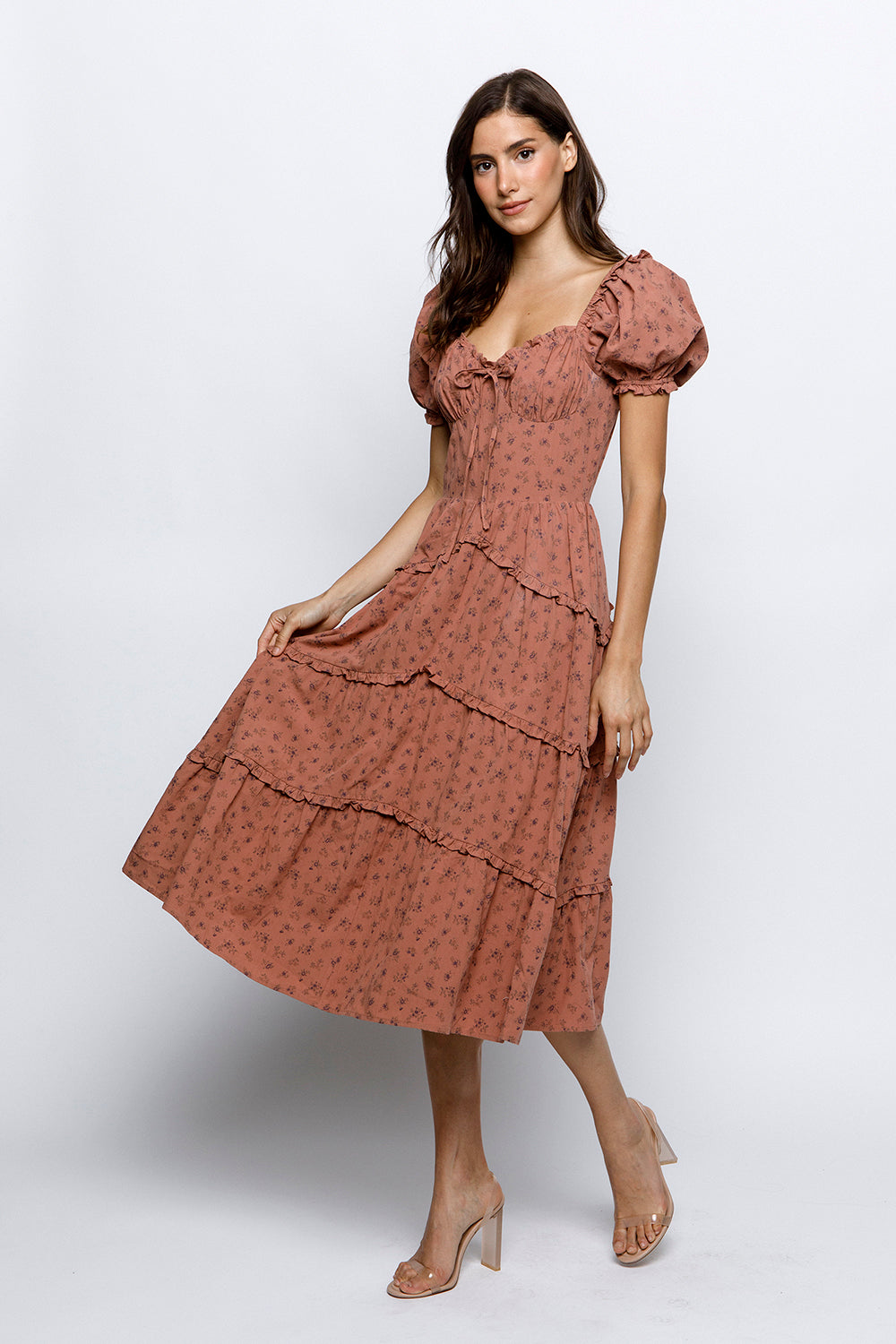 A model wearing a floral bustier midi dress with short puffy sleeves and a sweetheart neckline.
