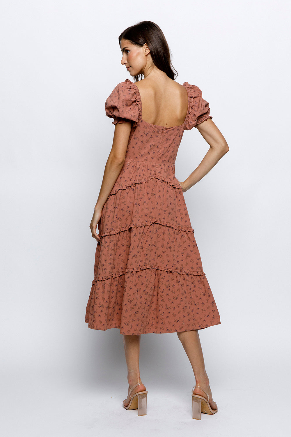 Back view of a woman wearing a mauve floral dress on a white background