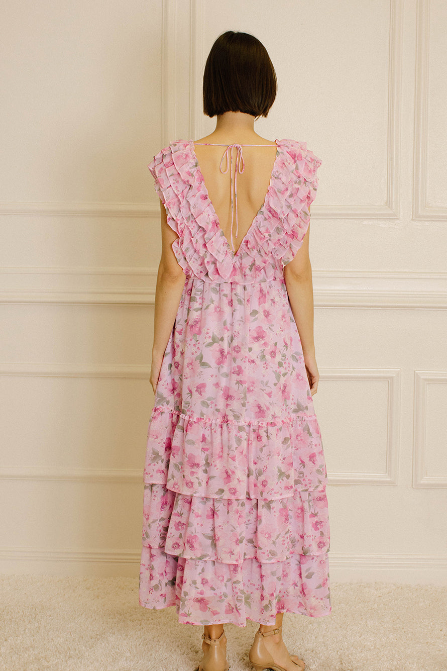 Back view of a woman wearing a pink floral dress against a neutral wall.