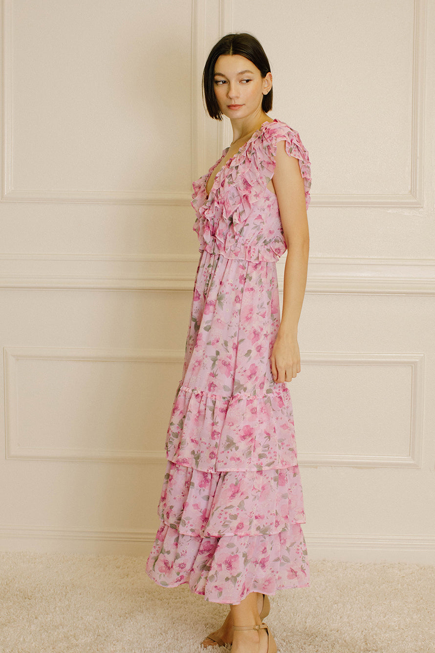 Side view of a woman wearing a pink floral dress against a neutral wall.