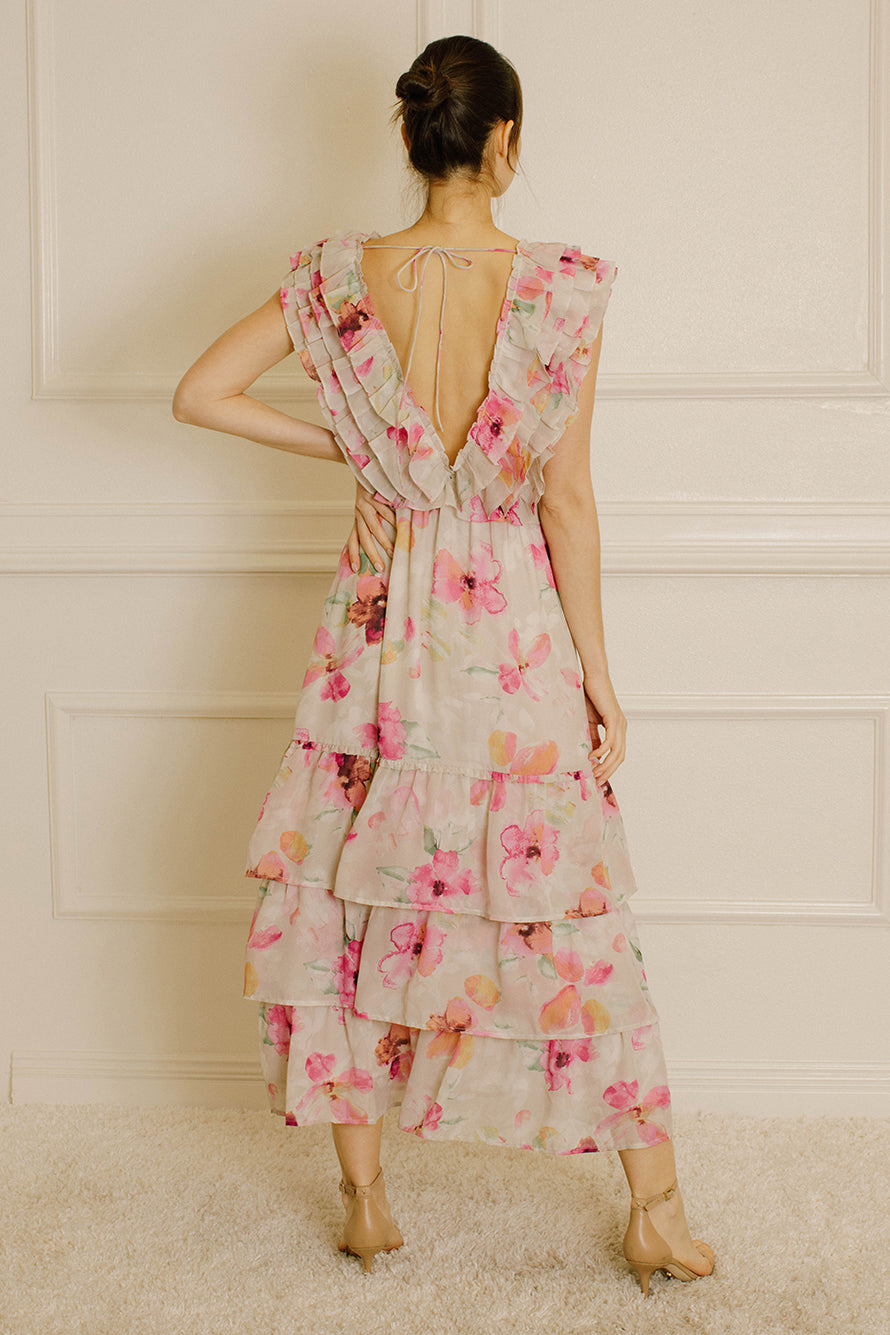 Back view of a woman wearing a grey and pink floral dress against a white paneled wall.