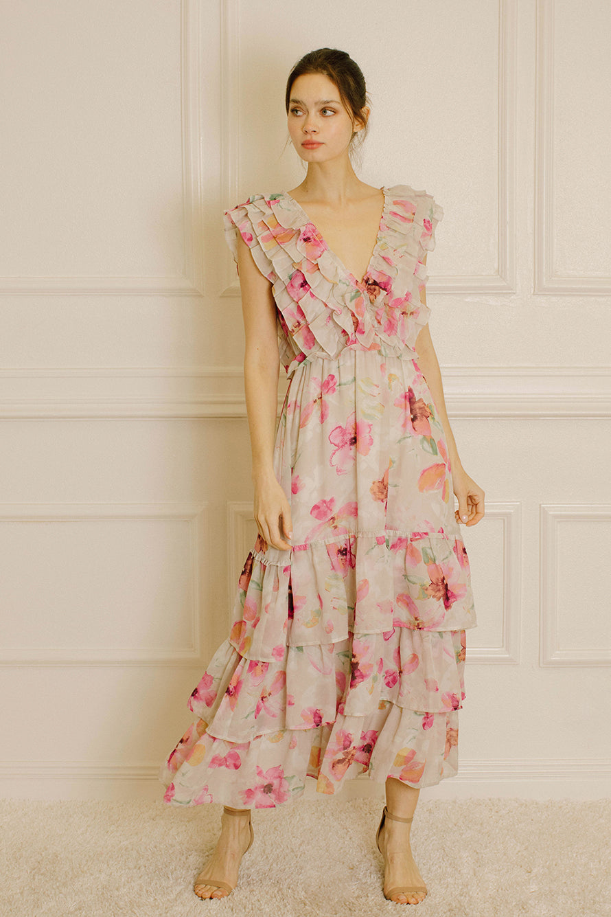 Woman wearing a grey and pink floral dress against a white paneled wall