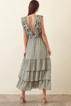 Back view of a woman wearing a green tiered dress against a plain background