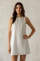 Woman wearing a polka dot dress against a plain background