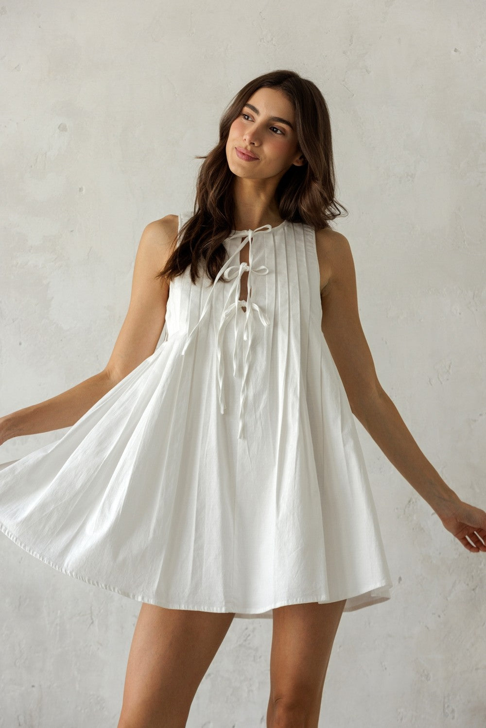 Woman wearing a white dress against a plain background