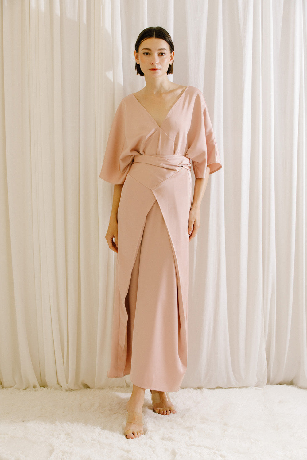 Front view of a woman wearing a pink V-neck maxi dress with fluid drape