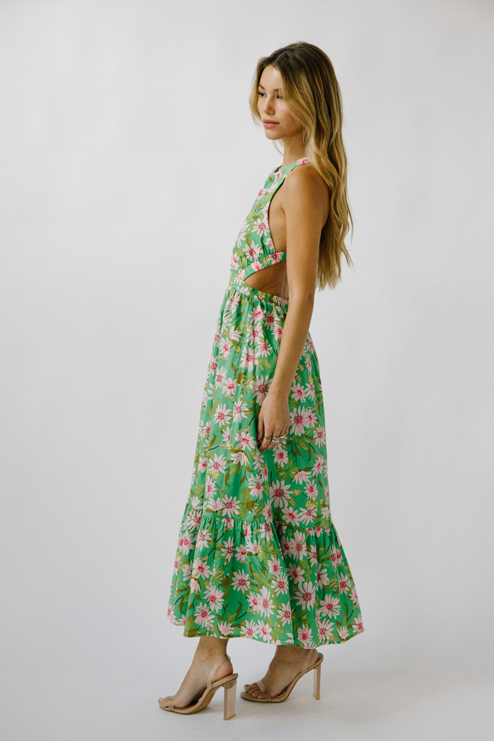 Side view of a woman wearing a green floral dress on a white background