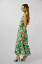 Side view of a woman wearing a green floral dress on a white background