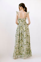 Back view of a woman wearing a floral dress with a white background
