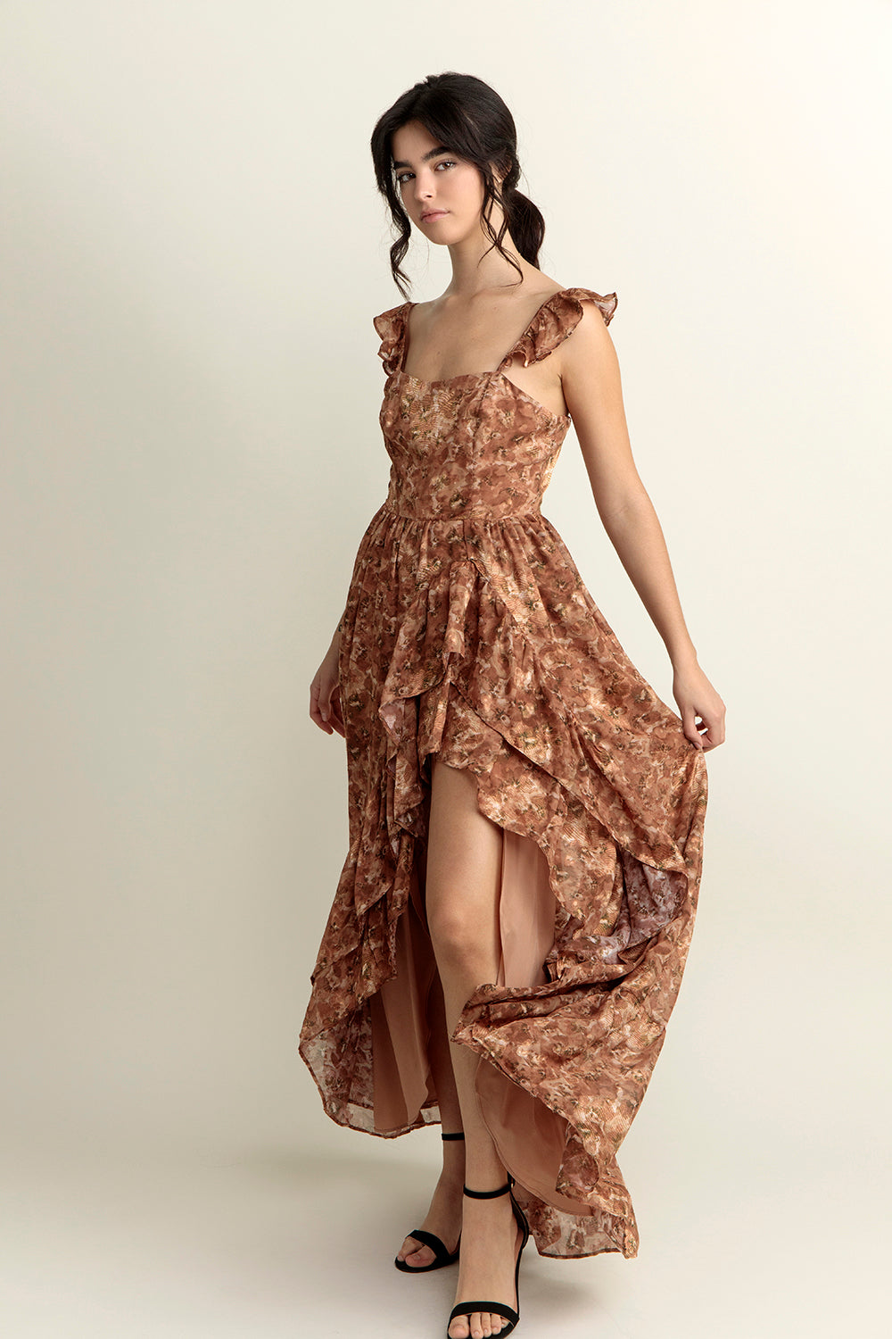 Woman wearing a brown floral dress with a slit on a white background