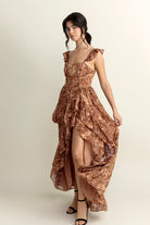 Woman wearing a brown floral dress with a slit on a white background