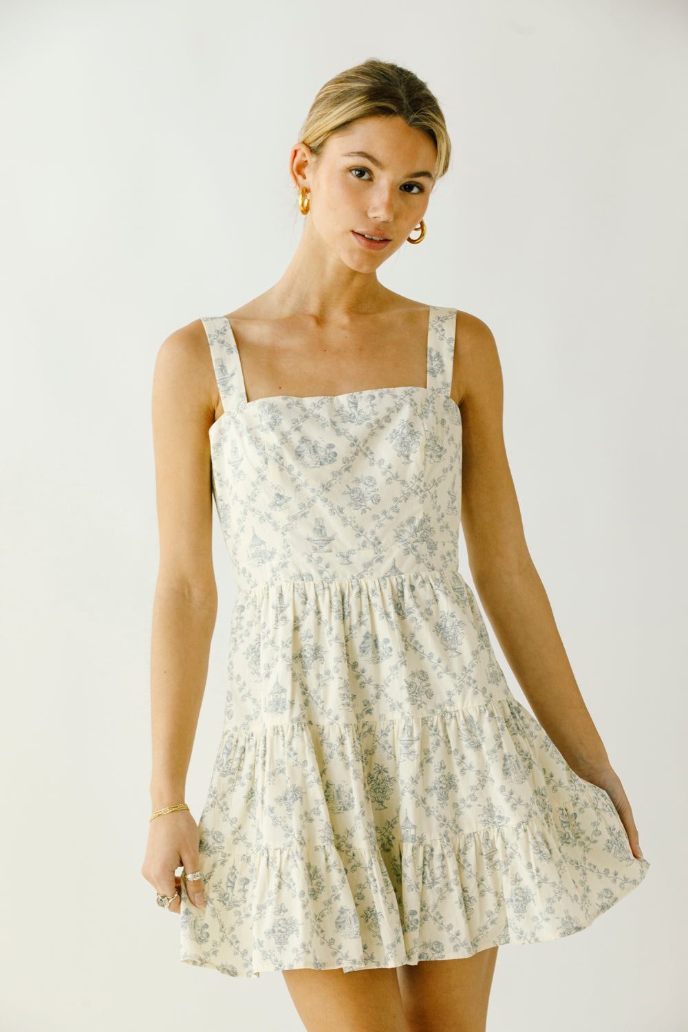 Woman wearing a cream floral dress against a plain background