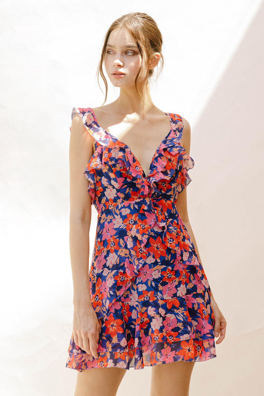 Woman wearing a colorful floral dress against a plain background