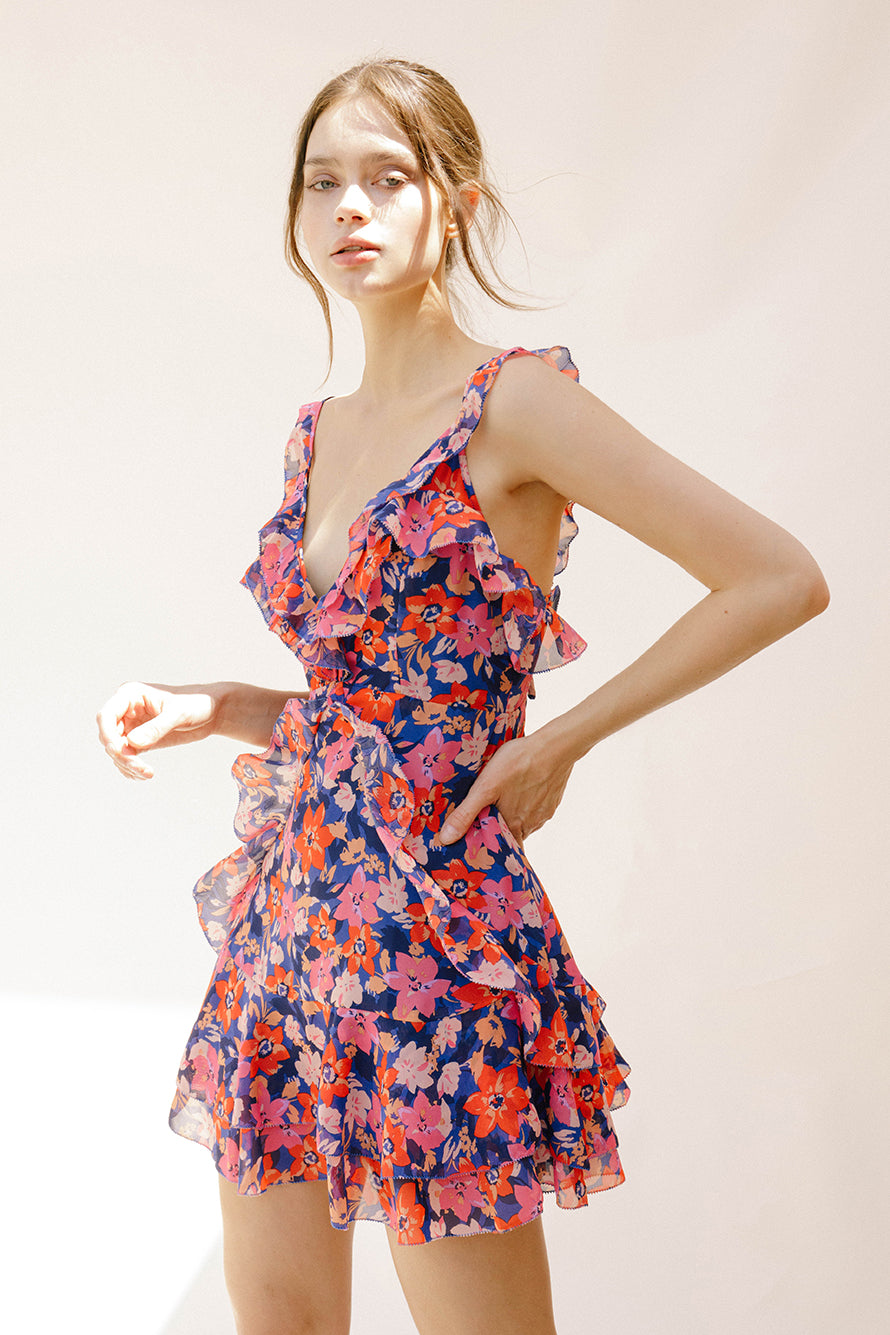 Side view of a woman wearing a colorful floral dress against a plain background