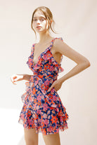 Side view of a woman wearing a colorful floral dress against a plain background