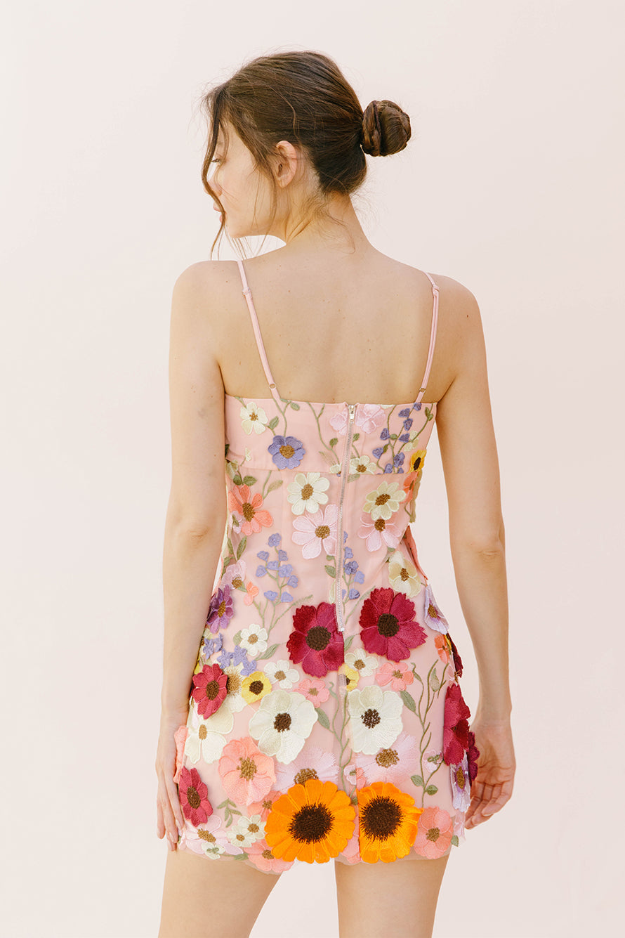 Back view of a woman wearing a floral dress on a plain background
