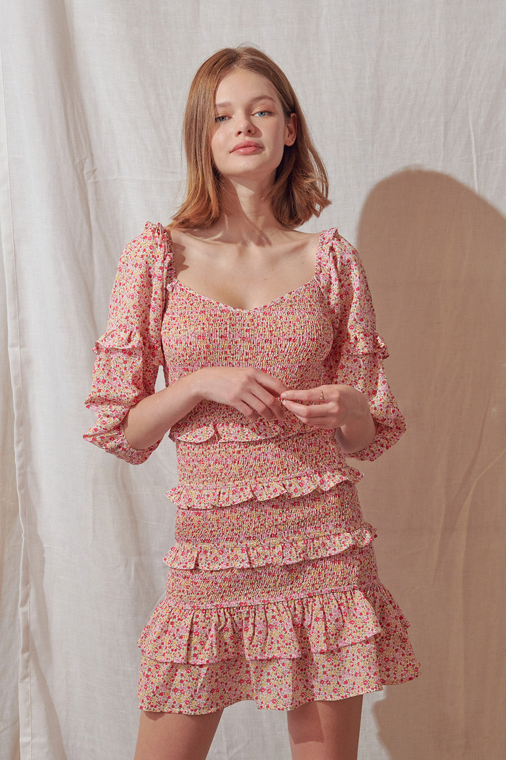Woman wearing a pink floral dress against a plain background