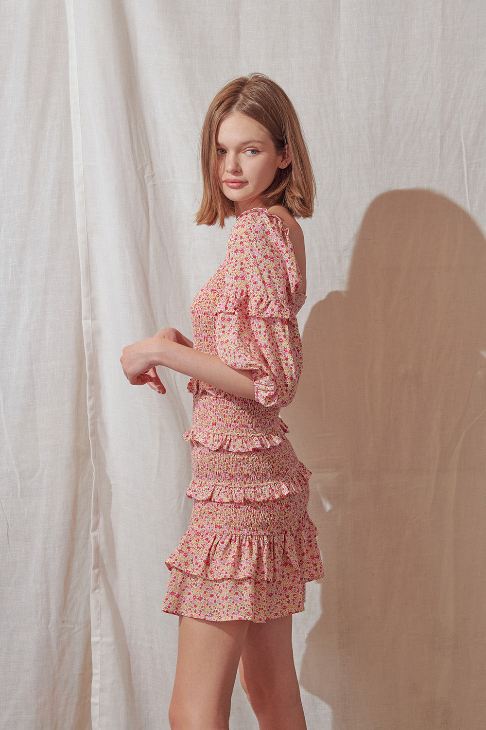 Side view of a woman wearing a pink floral dress against a plain background