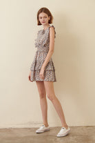 Woman wearing a blue floral dress and white shoes on a beige background