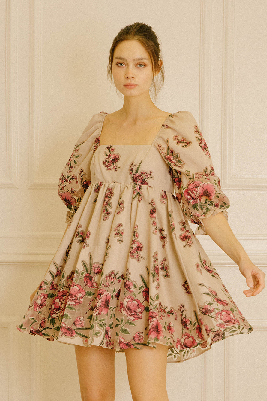 Woman wearing a floral dress against a neutral background