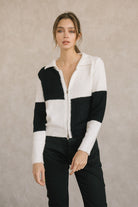 Woman wearing a black and white checkered zip-up sweater against a beige background