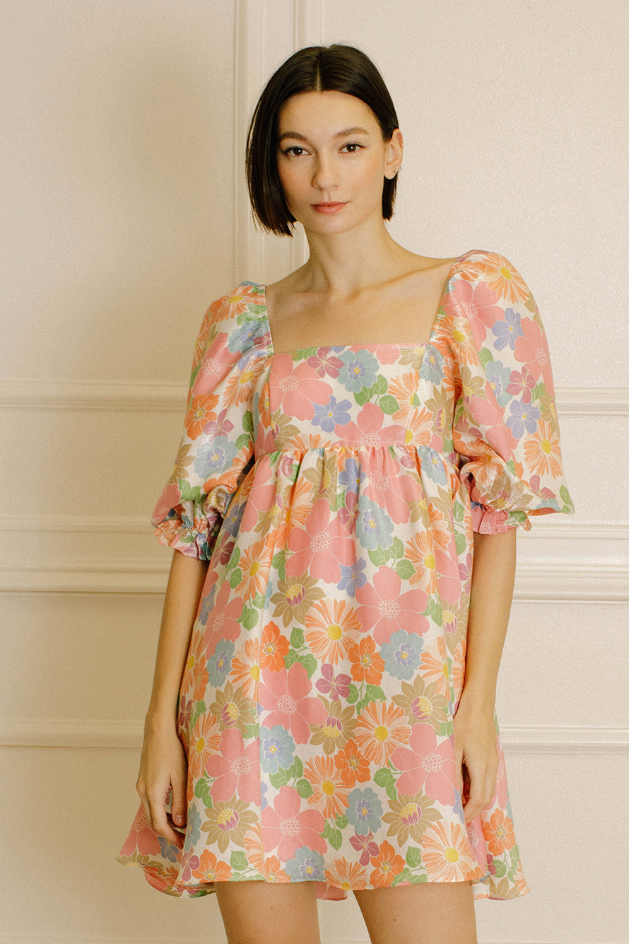Woman wearing a floral dress against a neutral background