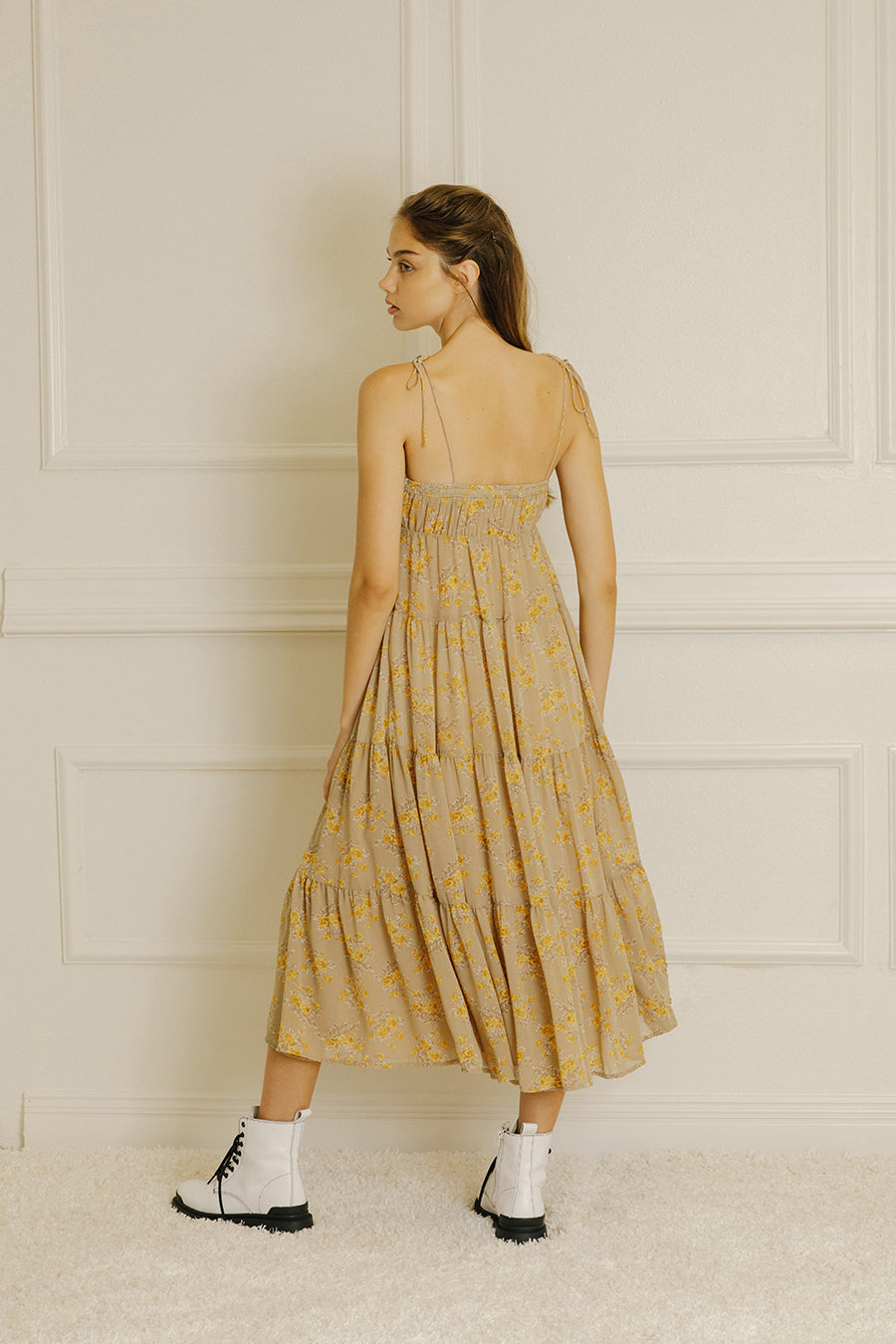Back view of a model wearing a yellow floral maxi dress and white boots