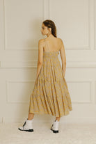 Back view of a model wearing a yellow floral maxi dress and white boots