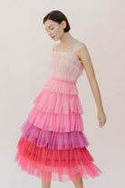 Woman wearing a pink ombre tulle tiered dress against a white background