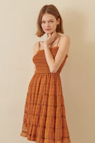 Woman wearing a rust-colored dress against a beige background