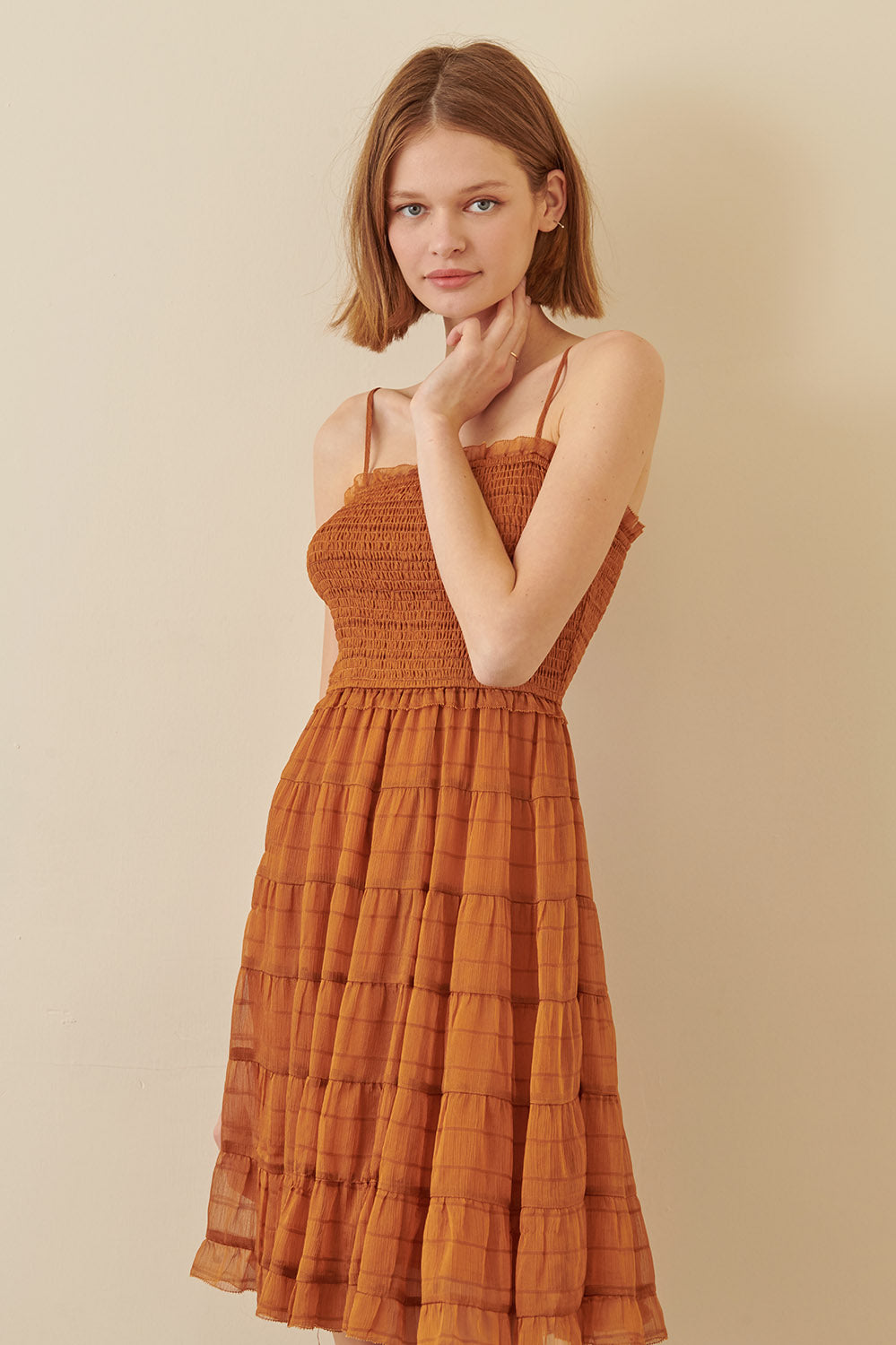 Woman wearing a rust-colored dress against a beige background