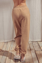 Back view of beige pants standing against a white curtain.