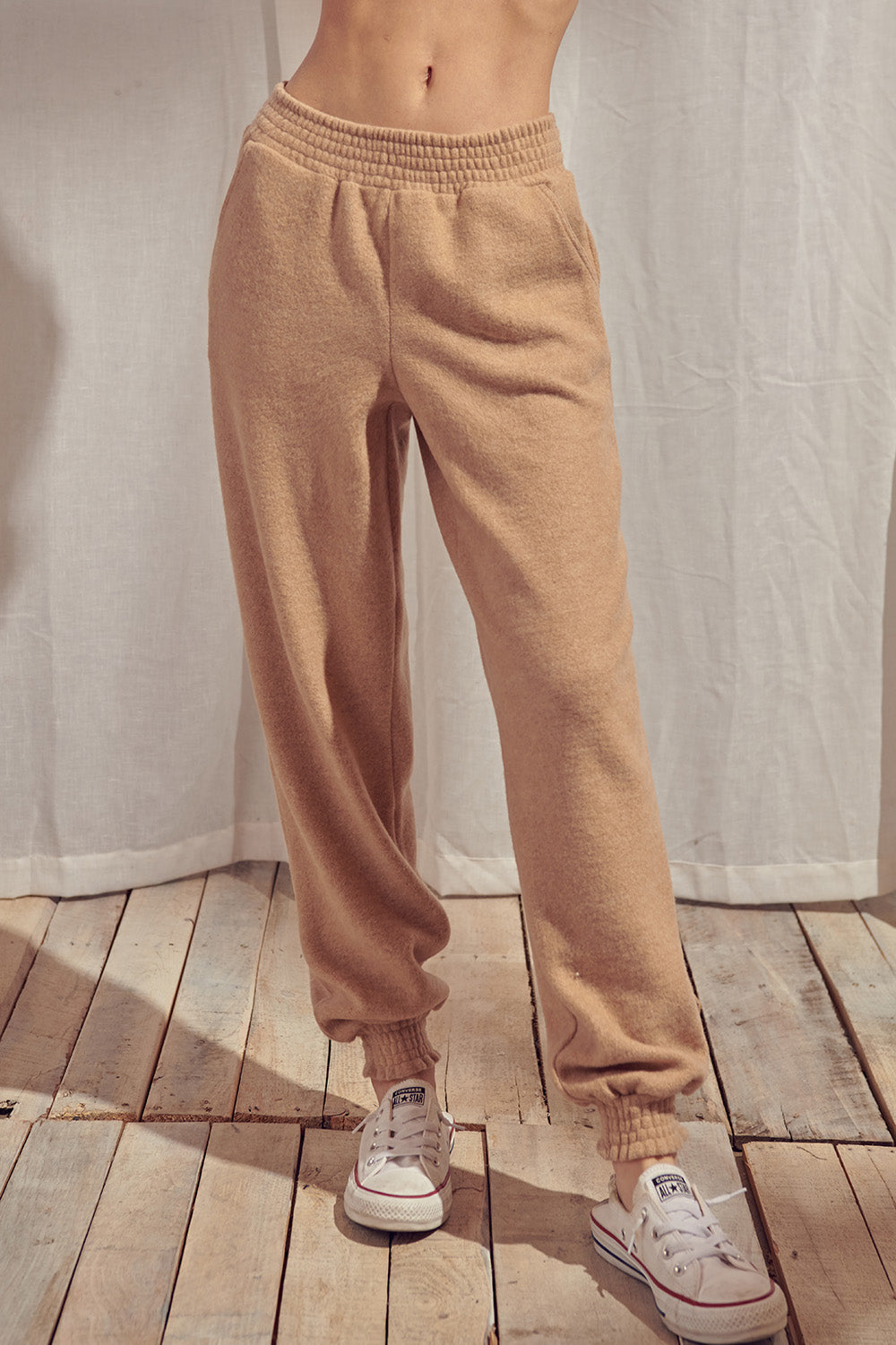 Beige pants standing against a white curtain.